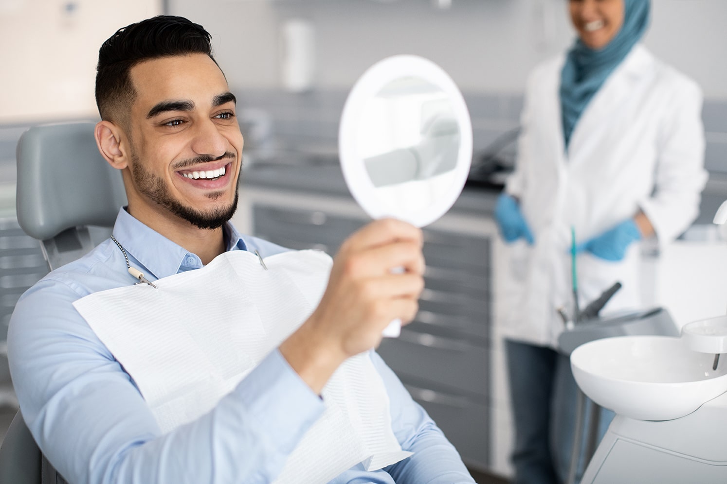 dental patient looking into a mirror after veneer treatment at cox family dentistry